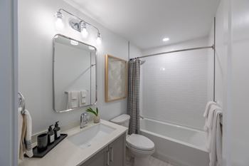 A white bathroom with a toilet, sink, and shower.
